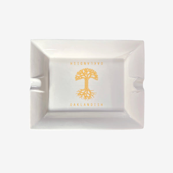White ceramic ashtray with yellow Oaklandish tree logo and wordmark in the center.