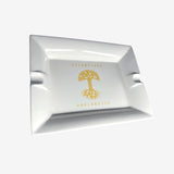 White ceramic ashtray with yellow Oaklandish tree logo and wordmark in the center.