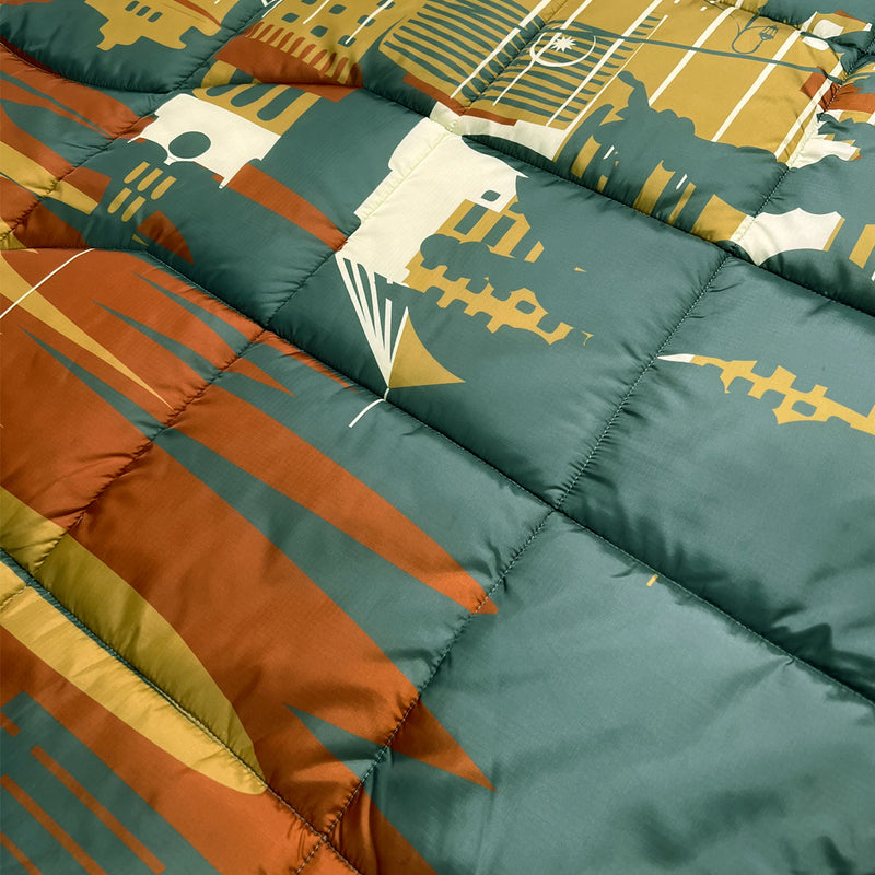 Detailed close-up of a puffy blanket with Oakland cityscape in blue, gold, rust and white.
