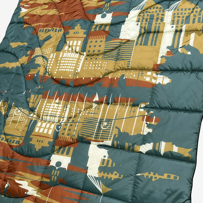 Close up of puffy blanket with Oakland cityscape in blue, gold, rust and white.