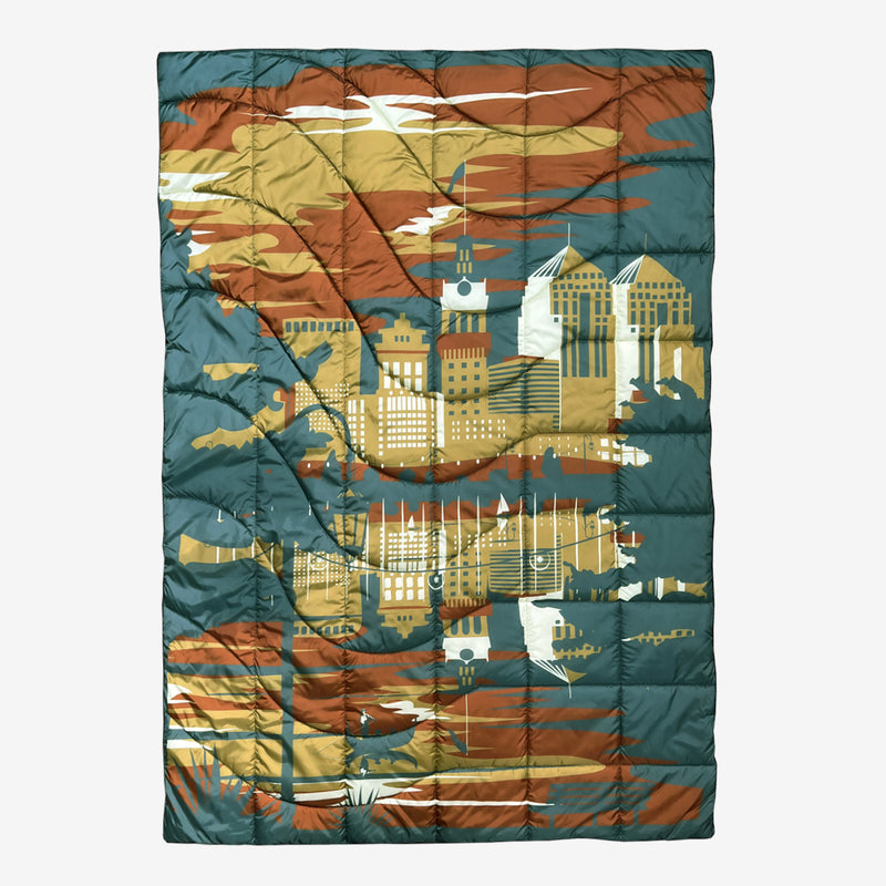 Puffy blanket with Oakland cityscape in blue, gold, rust and white.
