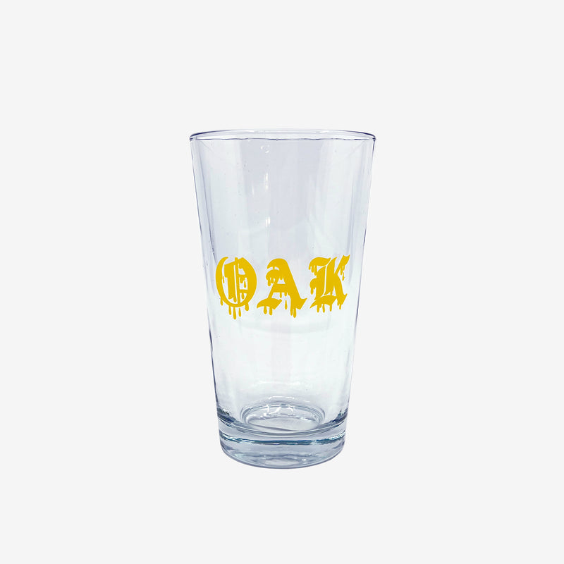 Clear glass pint beer glass with gold OAK wordmark in a bleed font.