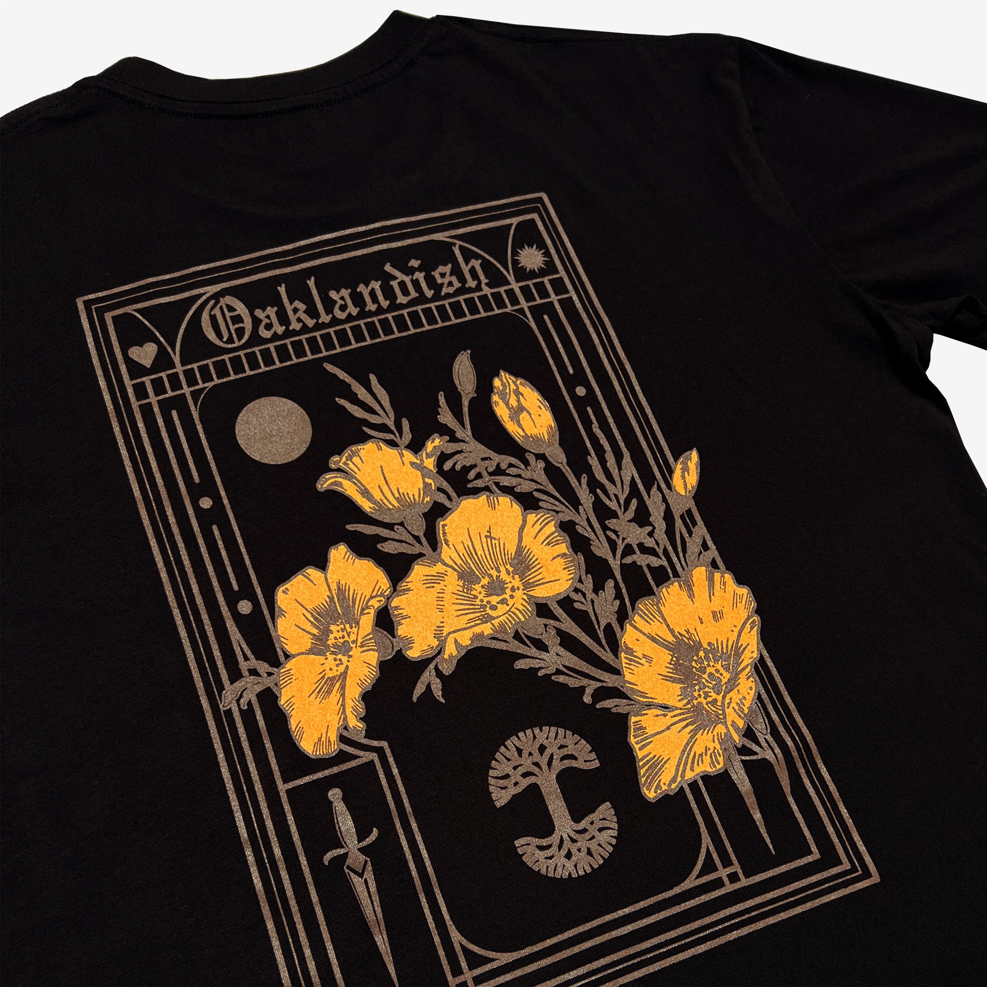Close-up of the backside of a black cotton t-shirt with California poppies, an Oaklandish wordmark, and a tree logo.
