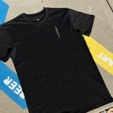 The front side of a black cotton t-shirt with a sword graphic on the chest lying on the street. 