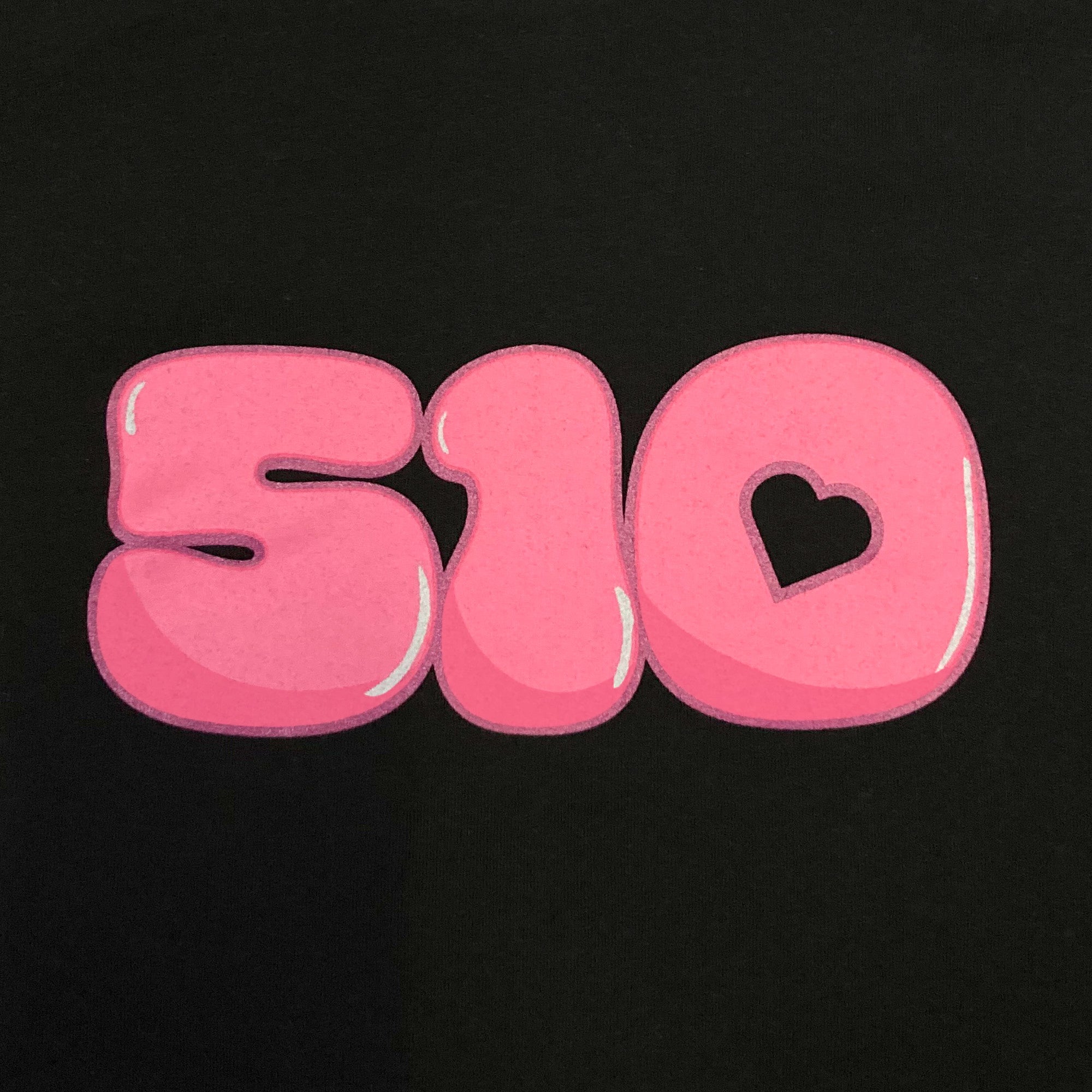 Detailed close-up of pink bubble numbers 510 graphic with the hole in the 0 shaped as a heart one a Women's black t-shirt.