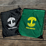 Flat image of black and forest drawstring bags outside on wooden bench in natural lighting.