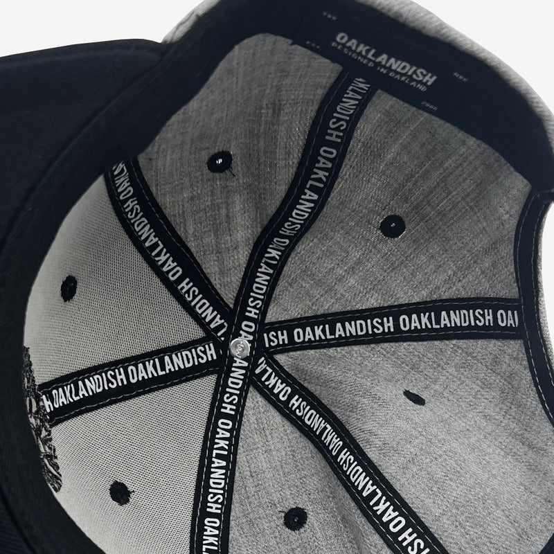 The underside of a grey Oaklandish cap with Oaklandish wordmarks on the taping and Oaklandish tag.