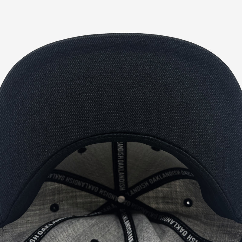 The underside of a grey Oaklandish cap with Oaklandish wordmarks on the taping and Oaklandish tag.
