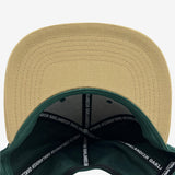 Khaki flat under brim angle with Inside forest snapback hat crown with ‘OAKLANDISH’ wordmark on black striping .
