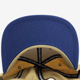 Navy flat under brim angle with Inside tan snapback hat crown with ‘OAKLANDISH’ wordmark on black striping .