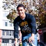 A man riding a bike in Oakland wearing a black t-shirt with All Gas No Breaks graphic.