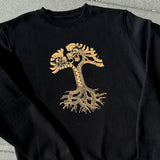 Black crewneck sweatshirt with metallic gold dragon power design in the shape of the Oaklandish tree logo outdoors on asphalt.