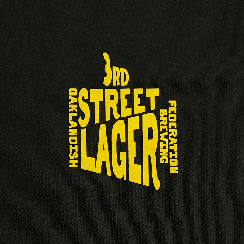Detailed close-up of 3rd Street Lagar wordmark on the front left chest wear side of a black t-shirt.