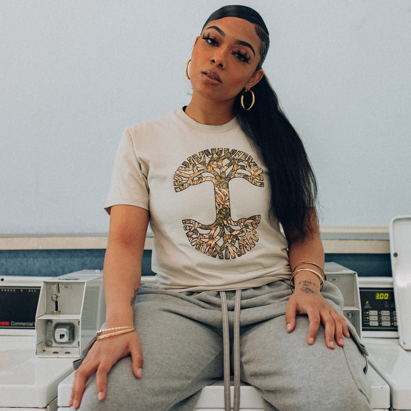Female model wearing men's bone t-shirt with floral pattern inside classic Oaklandish tree logo.