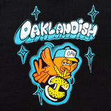 Close-up of a graphic image of a cartoon flying bird wearing an Oaklandish logo necklace around its neck and an Oaklandish bubble wordmark on a black t-shirt.