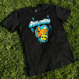Black t-shirt with a graphic image of a flying cartoon bird wearing an Oaklandish logo necklace with Oaklandish bubble wordmark lying on grass.