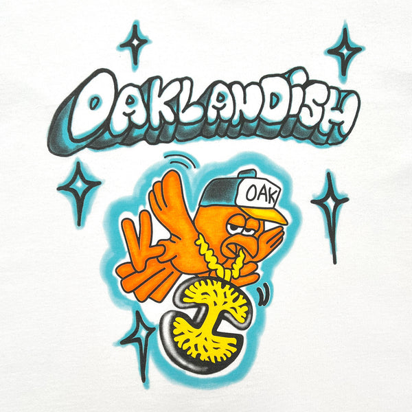 Close-up of a graphic image of a cartoon flying bird wearing an Oaklandish logo necklace around its neck and an Oaklandish bubble wordmark on a white t-shirt.