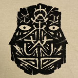 Detailed close-up of the black GATS mask silhouette on the chest of a mushroom brown t-shirt.