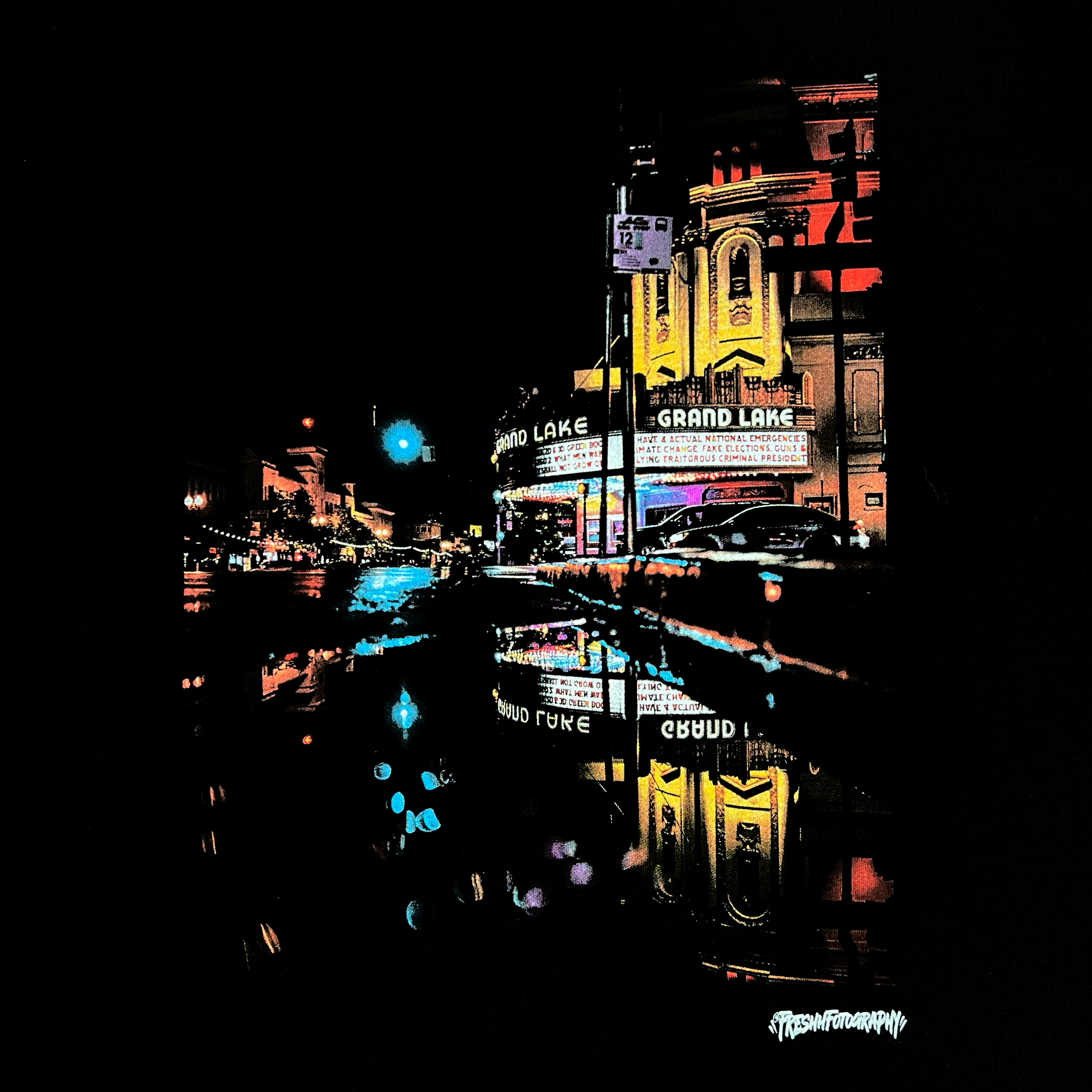 Detailed close-up of the image of a rainy night reflecting street lights and The Grand Lakes Theatre on a black t-shirt.