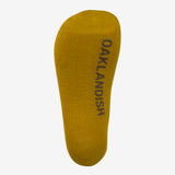 Single yellow men's crew socks. Bottom view with brown Oaklandish wordmark on sole.