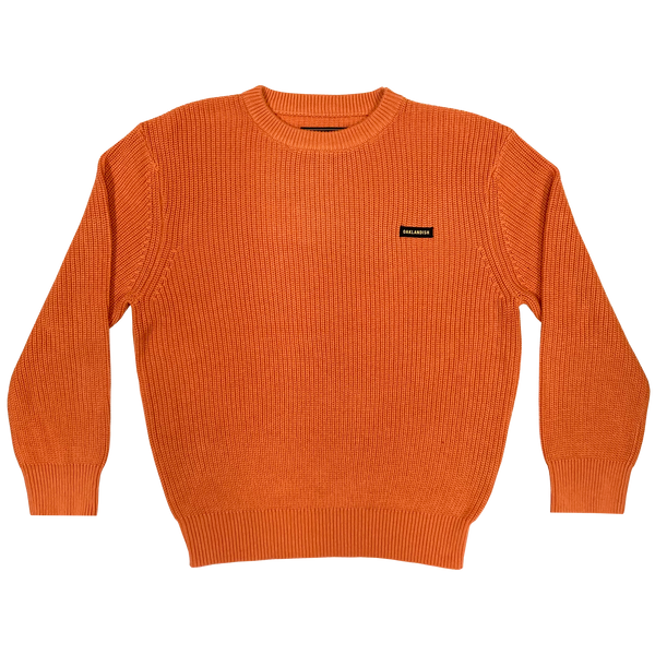 Heavy cotton knit sweater with embroidered Oaklandish wordmark woven label patch on front left chest in autumn orange.