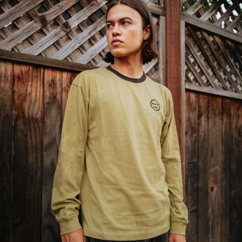 Army green long sleeve crew neck tee with black Hiero hip-hop logo on chest on man outdoors.