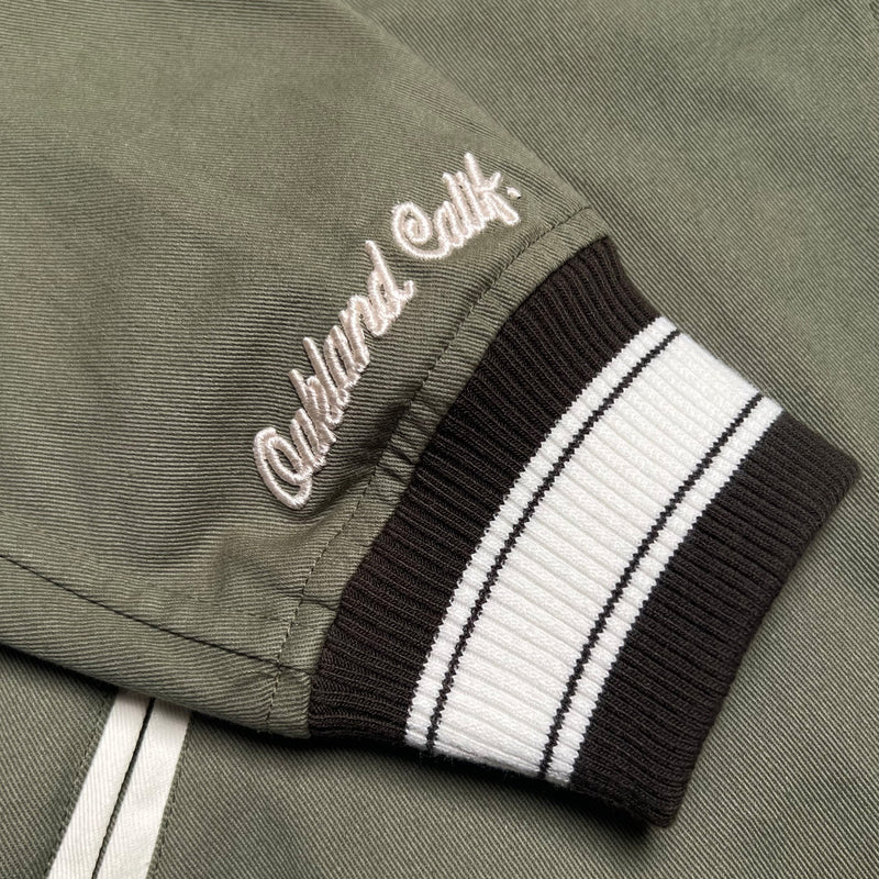 Detailed close-up image of 2x1 ribbing at cuffs and dimensional embroidery of 'Oakland Calif'' of Army Hiero Cadet jacket.
