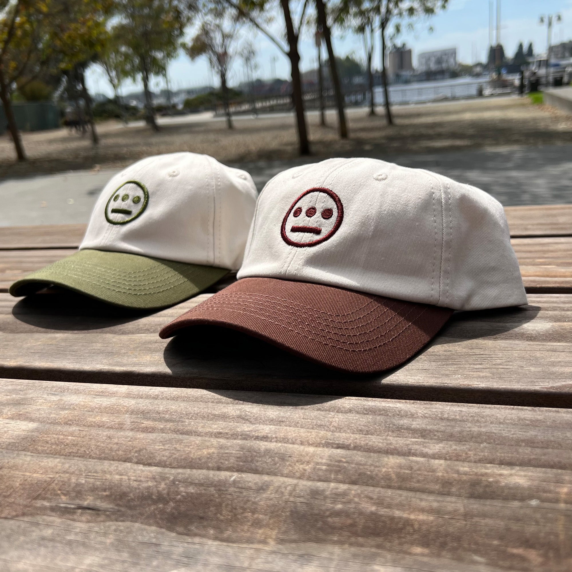 Photo image (left to right) of cream with olive logo and cream with brown logo dad hats with contrasting brims and embroidered logo