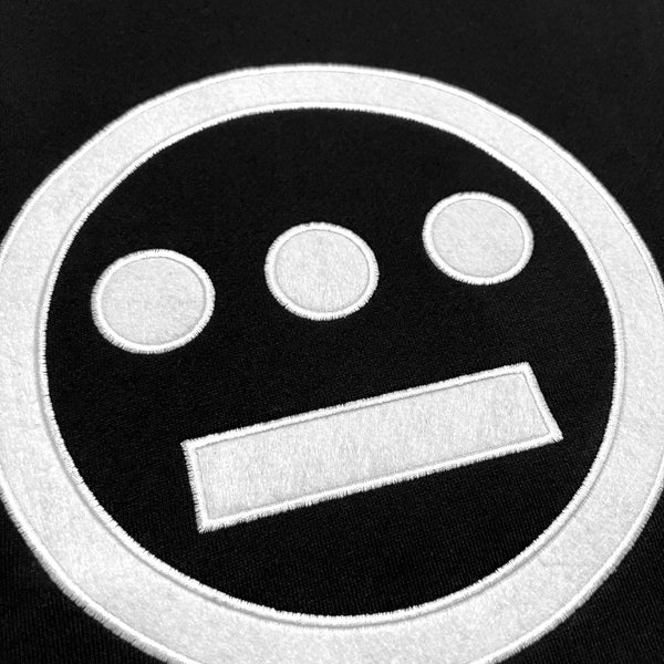 Close up of white felt Hiero hip-hop crew logo on black crew sweatshirt.