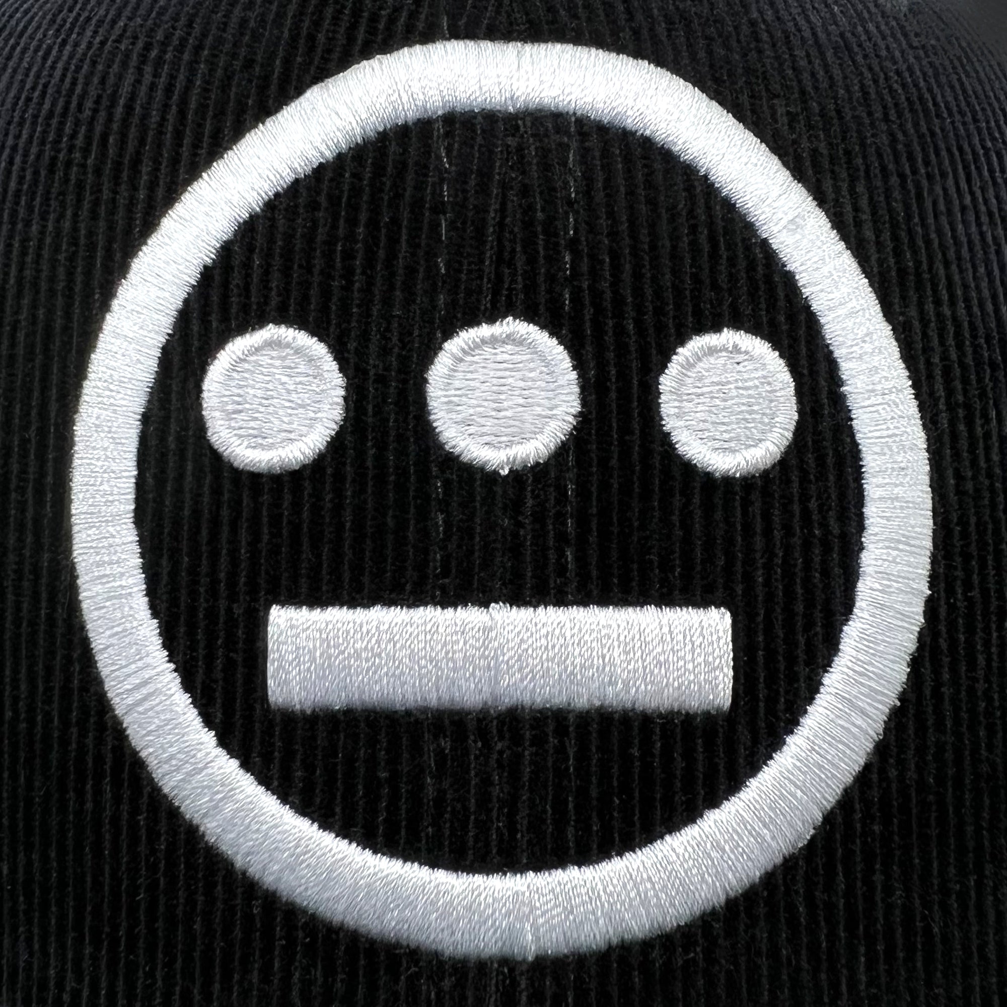 Detailed close up of embroidered white Hiero logo on black corduroy Mitchell & Ness snapback hat.