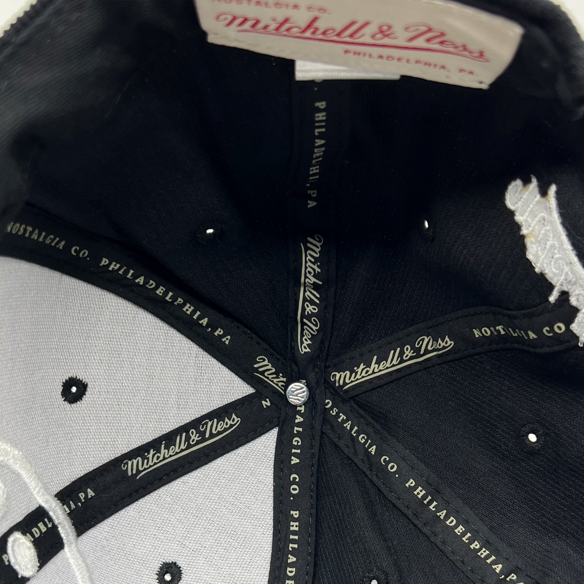 Detailed close up of Mitchell & Ness taping inside the crown of black cap.