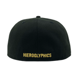 The backside of a black fitted New Era cap with gold embroidered Hieroglyphics wordmark.
