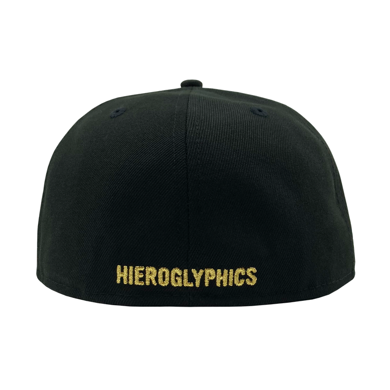 The backside of a black fitted New Era cap with gold embroidered Hieroglyphics wordmark.