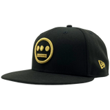 Side view of black New Era fitted cap with gold embroidered Hiero hip-hop logo on the crown.