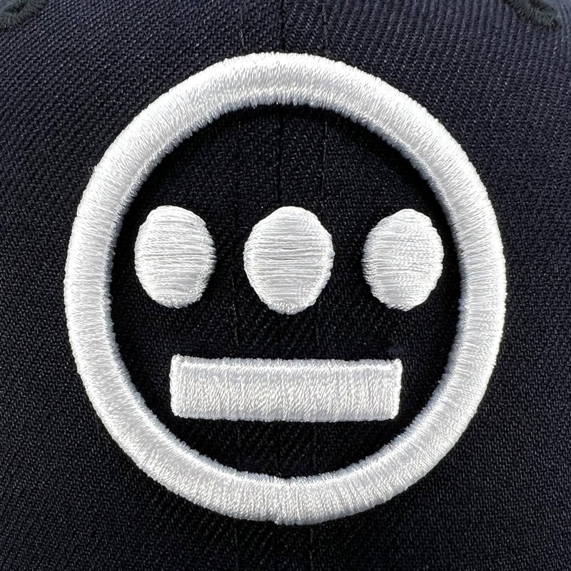 Detailed close-up of white embroidered Hieroglyphics hip-hop logo on the crown of navy New Era fitted cap.