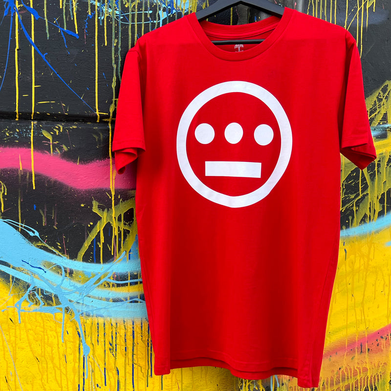 Red t-shirt with white Hieroglyphics Hip-Hop logo on center chest hanging on paint splattered wall.