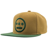 Side angle of two-toned brown Mitchell & Ness snapback cap with green embroidered green Hiero Hip Hop crew logo & green visor.