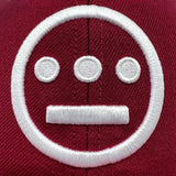 Detailed close-up of embroidered white Hiero hip-hop logo on a cardinal red Mitchell & Ness cap.