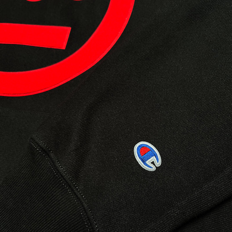 Close-up of Champion logo embroidered on the sleeve of a black hoodie.