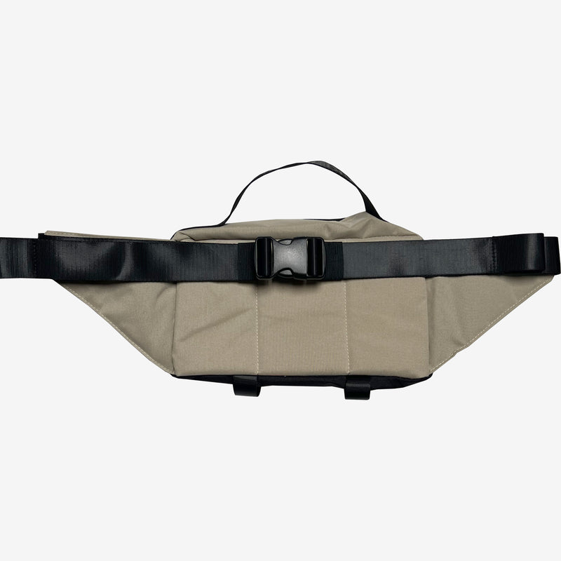 The backside of sand brown hip bag waist belt and top handle.