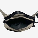 Top view of sand nylon hip bag with open top zipper to expose inside of bag and top handle with an Oaklandish wordmark.