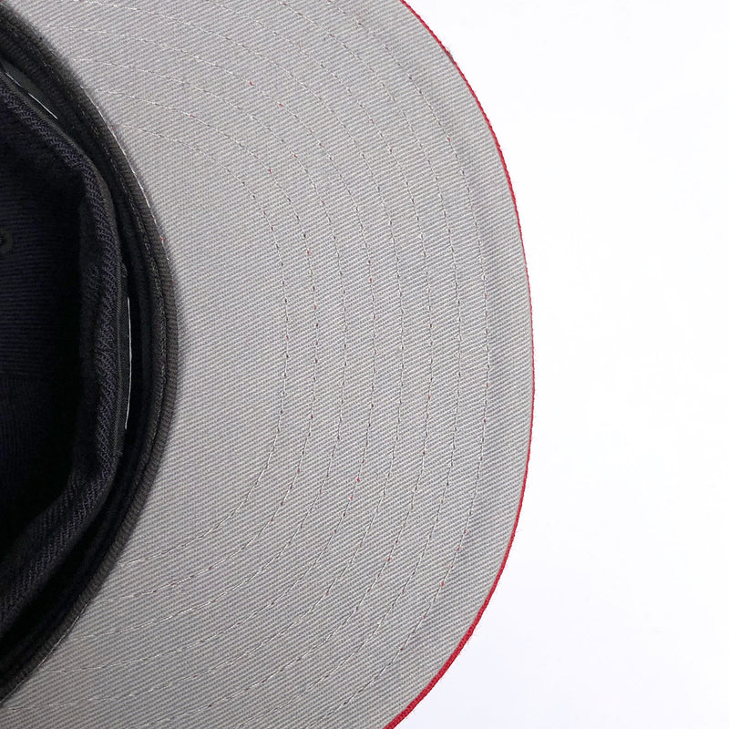 The grey underside of the bill of a New Era navy cap.