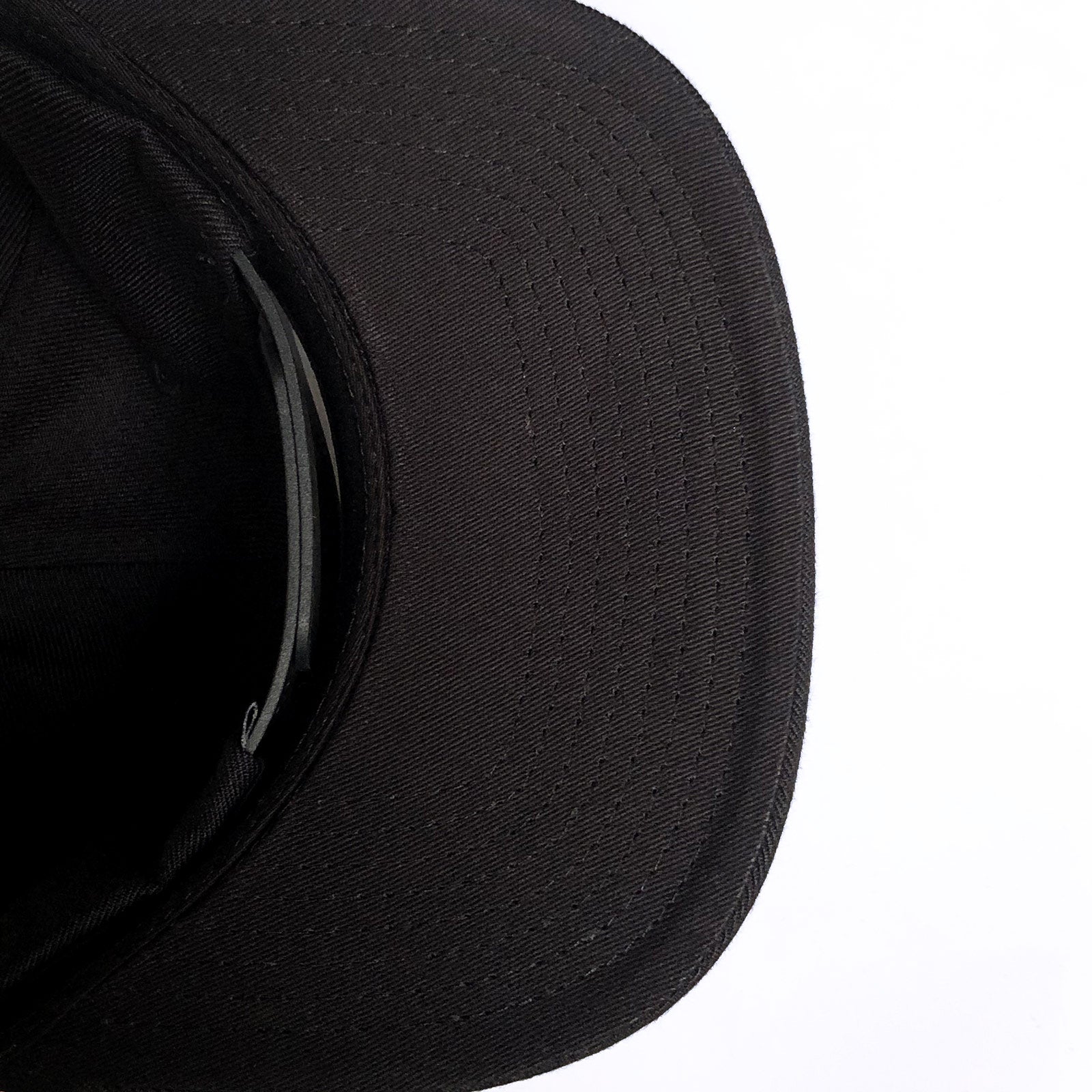 Black underside of the visor of a black baseball cap with adjustable strapback closure.
