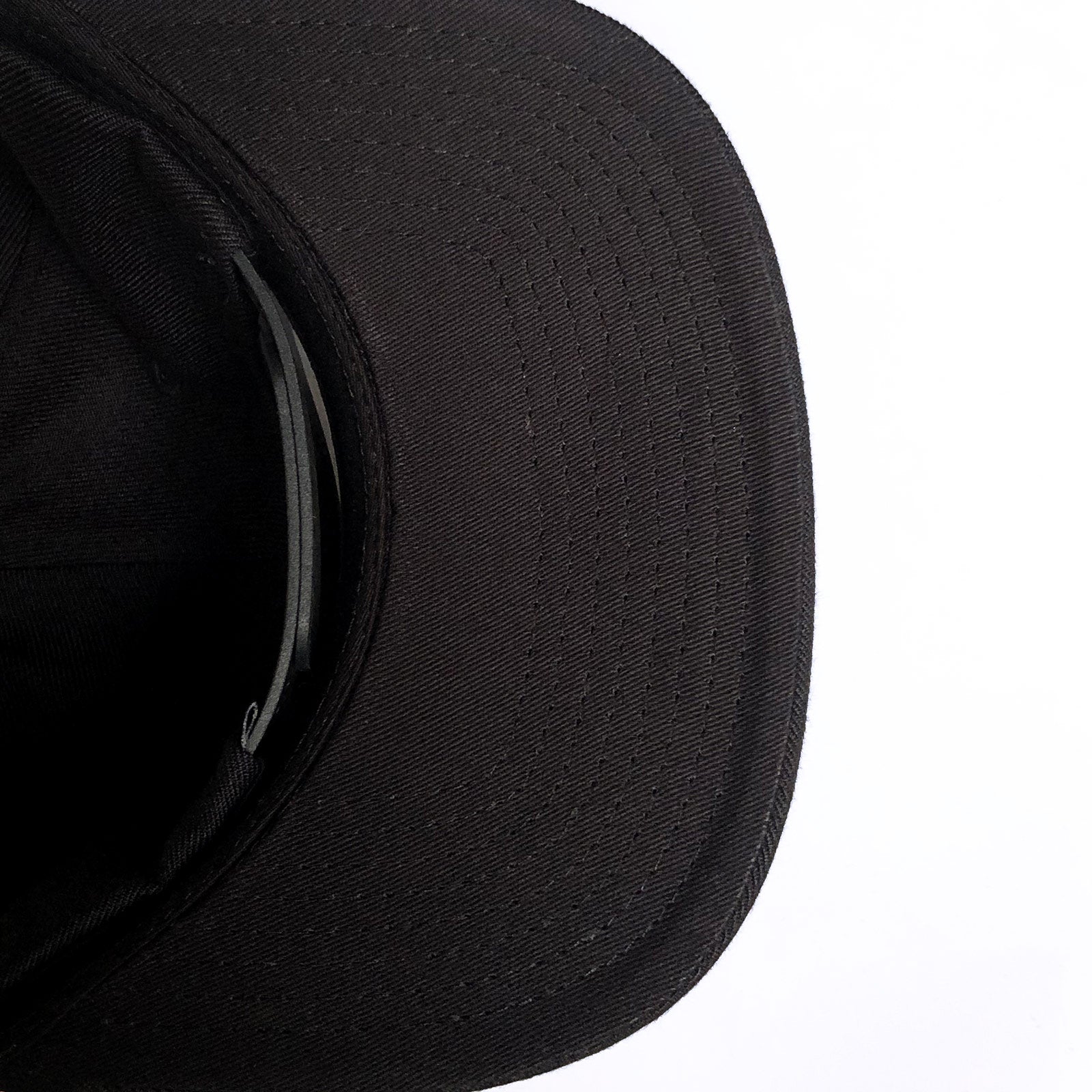 A close-up image of the Hiero Logo Snapback by Hieroglyphics, focusing on the brim. The brim shows visible stitching and curves slightly. The cap's interior is partially visible, revealing a dark sweatband and a small section of the adjustable snapback strap. The background is a plain, white surface.