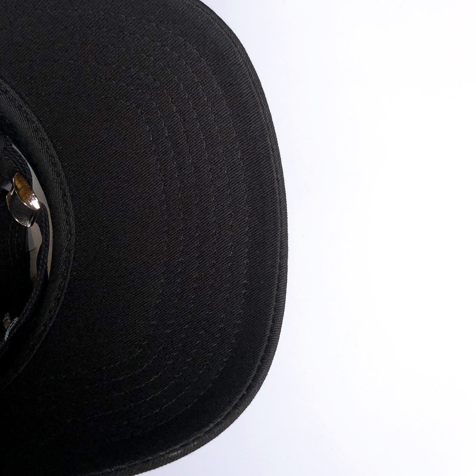 Black underside of the visor of a black dad cap. 