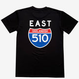 Backside of black t-shirt with white East wordmark above a red and blue highway sign with words Oaklandish 510 inside.