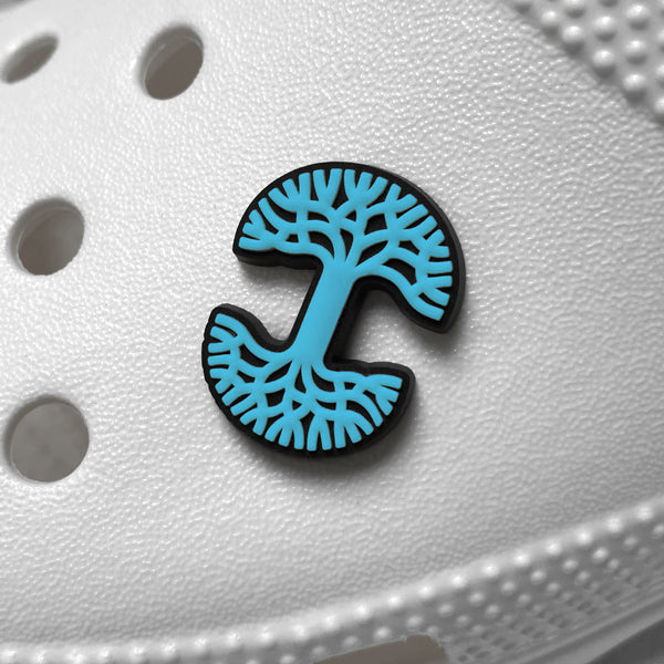 Teal and black Oaklandish tree logo shoe charm on a white croc shoe.
