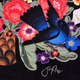 Close up of blue bird and artist signature in graphic designed by artist Jet Martinez on a black women’s t-shirt.
