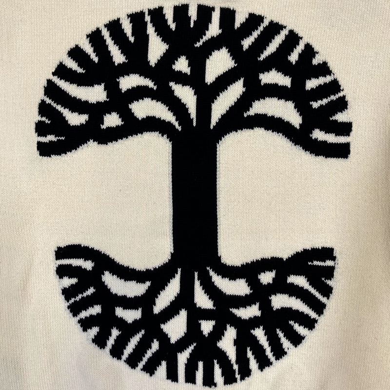 Detailed close-up of large black Oaklandish tree logo on the back of a white, heavy-knit sweater.