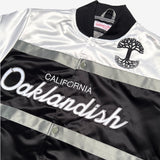 Close-up of the black Oaklandish tree logo and Oaklandish California wordmark on the chest of a striped satin jacket.